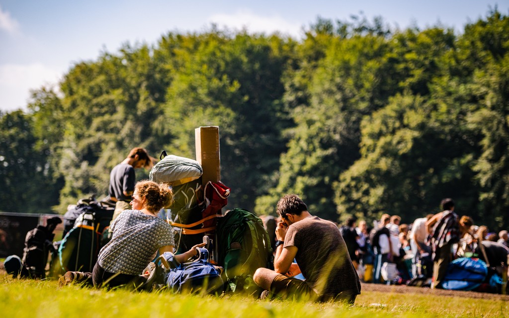Bezoekers zitten met met bagage in het gras Bezoekers zitten met met bagage in het gras