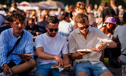 Drie bezoekers genieten van een pizza Drie bezoekers genieten van een pizza